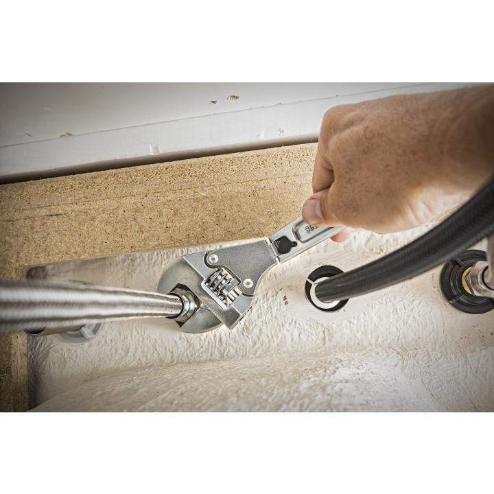 Adjustable wrench tightening plumbing fitting under sink with flexible hoses