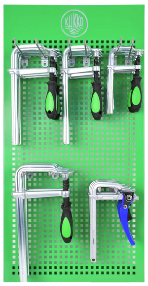 Metal clamps with green and black handles on a green perforated tool board
